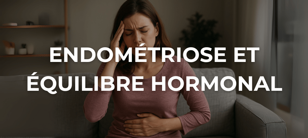 Femme assise sur un canapé, main sur le ventre et visage crispé, souffrant de douleurs liées à l’endométriose.
